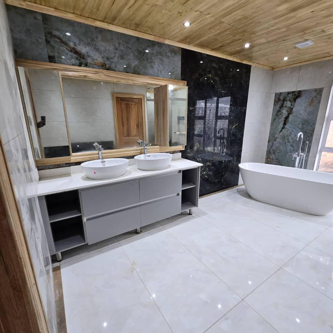 Luxury bathroom with a grey double vanity, freestanding tub and dark marble feature wall.