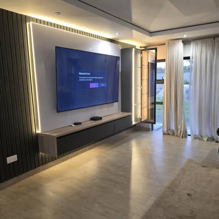 Entertainment wall with black timber slat panelling, LED cove lighting and a floating console.
