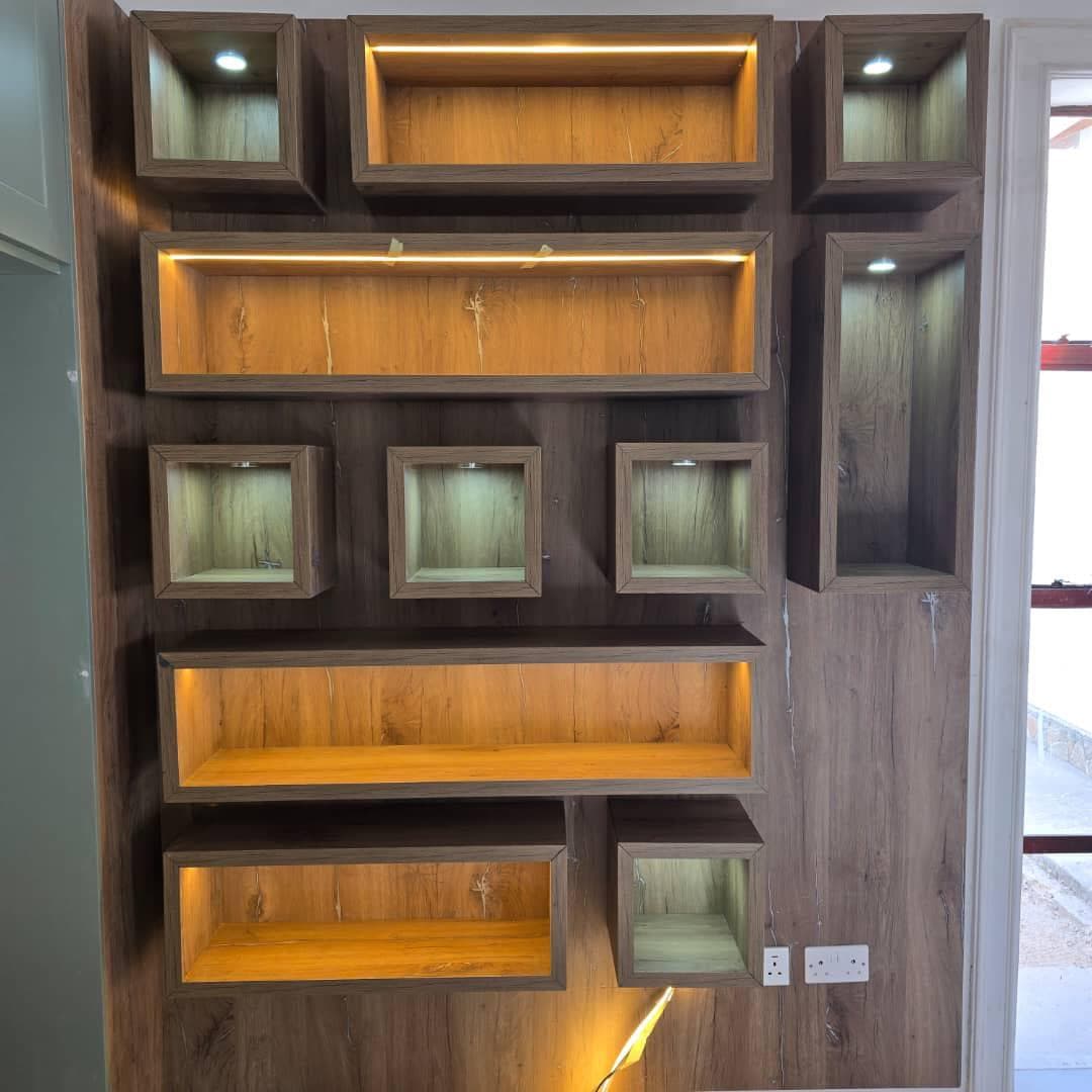 Feature wall of geometric display niches in oak, individually lit.