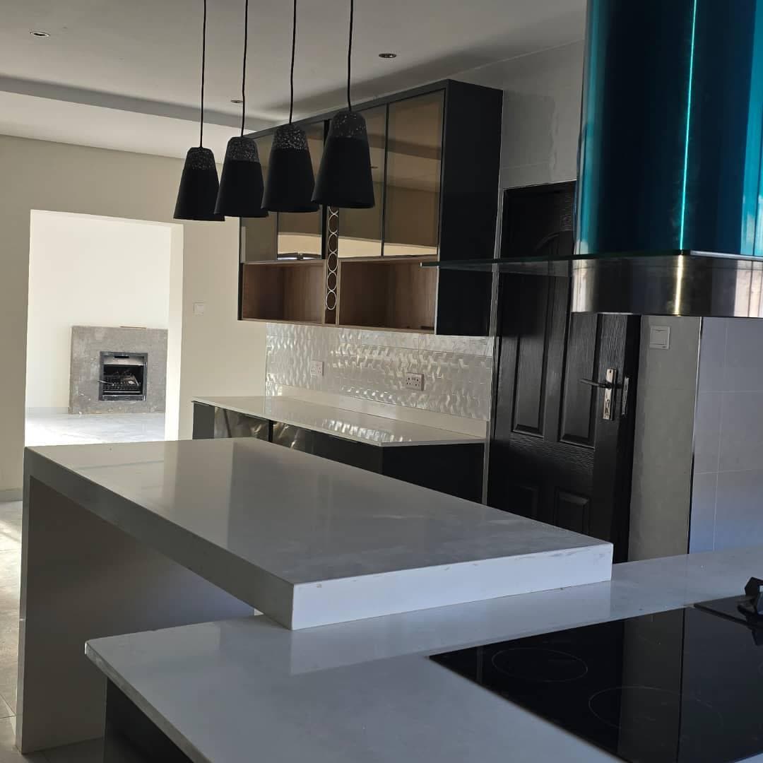 Contemporary kitchen with dark cabinetry, mirrored splashback and a quartz breakfast bar.