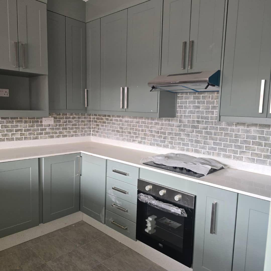 Sage green shaker kitchen with white quartz tops and a brick mosaic splashback.