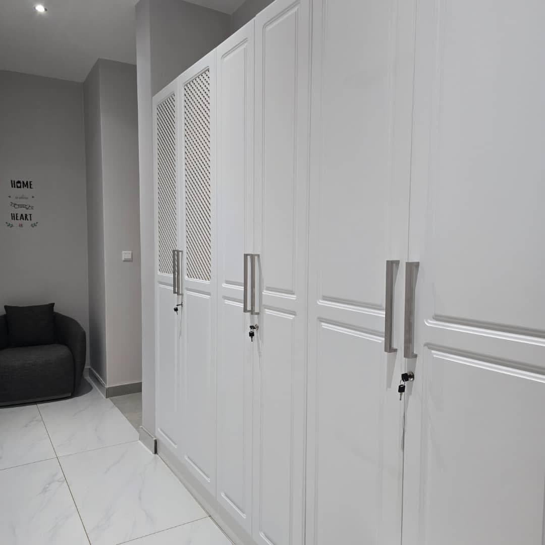 White gloss wardrobes with moulded panel doors and ventilated mesh inserts.